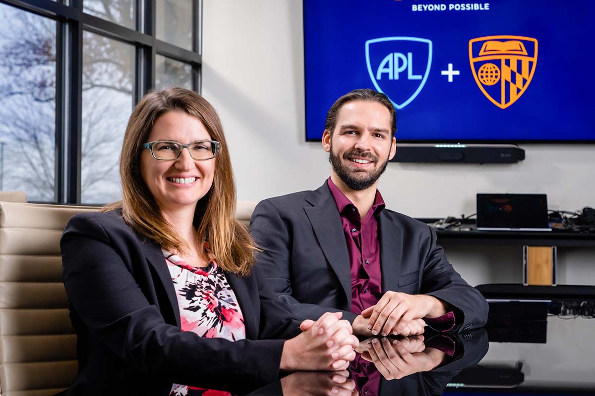 WSE PI Amy Foster, Ph.D., and APL PI Nicholas G. Pavlopoulos, Ph.D. are seated beside each other at a reflective black table in a conference room.