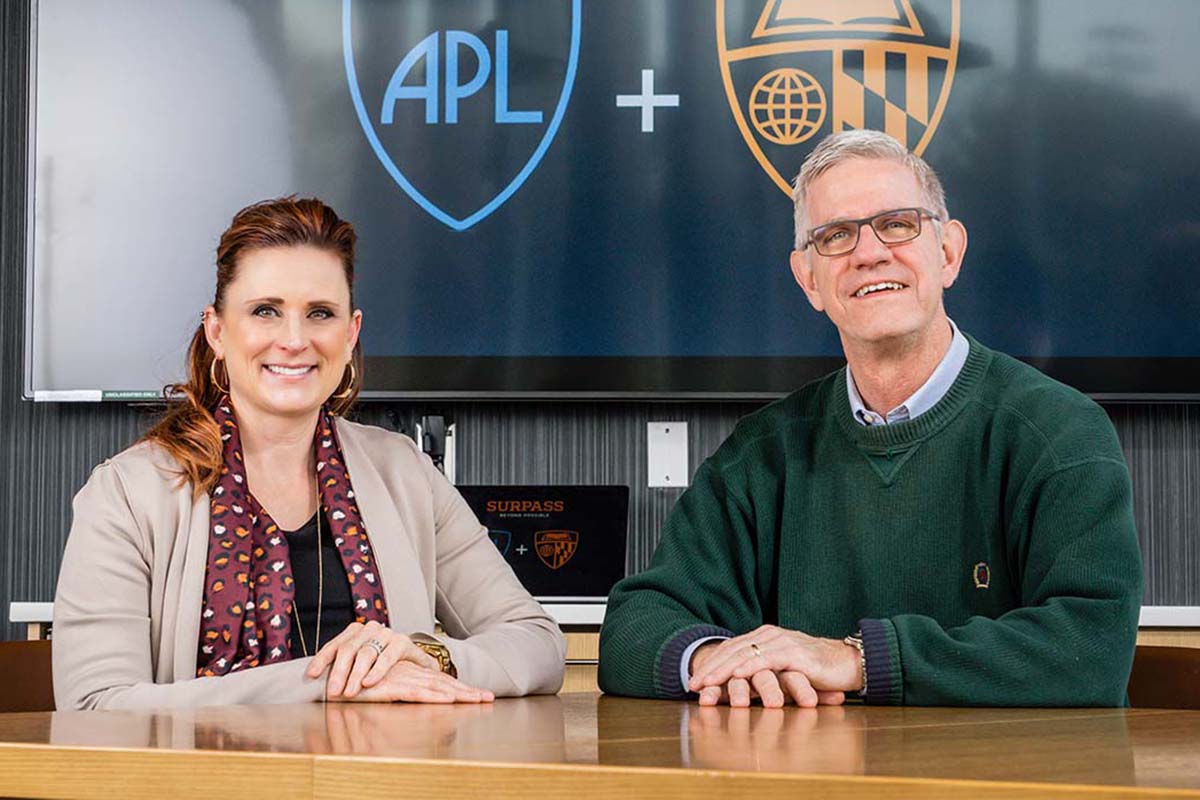 APL PI Melissa Terlaje, Ph.D., and WSE PI Kevin Hemker, Ph.D., sit beside each other at a wooden table in a conference room.